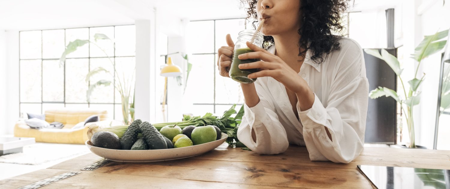 Young african american woman drinking green juice